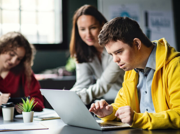 Two adults are helping a child work on a laptop